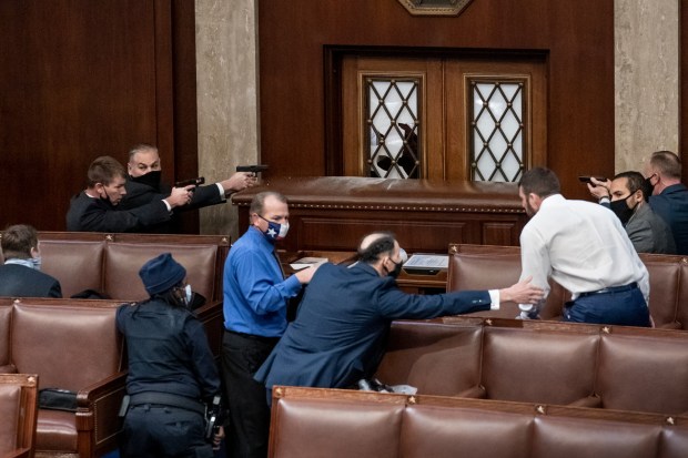 FILE - Security forces draw their guns as rioters loyal to President Donald Trump try to break into the House of Representatives chamber to disrupt the Electoral College process, at the Capitol in Washington, Jan. 6, 2021. (AP Photo/J. Scott Applewhite, File)