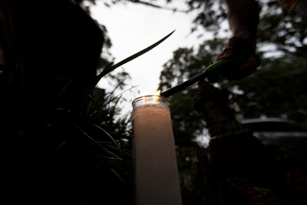 A candle is lit for people gathered for an energy healing ritual at the Fairy Tree in Norfolk, Virginia, on Aug. 8, 2024. (Billy Schuerman / The Virginian-Pilot)