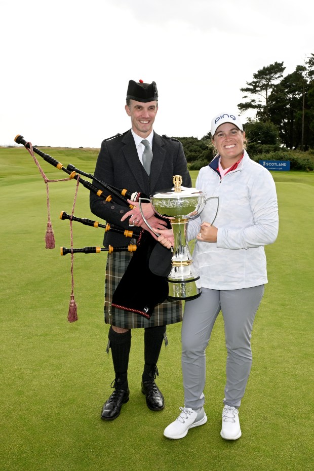 Lauren Coughlin poses with the trophy and a bagpiper after winning the Women's Scottish Open on Sunday at Dundonald Links Golf Course. PAUL DEVLIN/GETTY