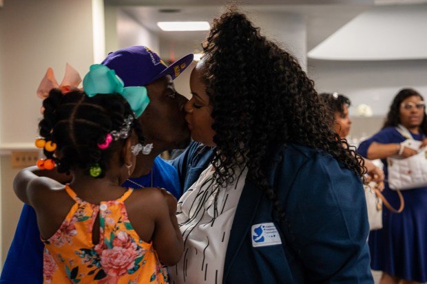 Bristeria Clark kisses her husband while he holds their daughter after the commencement ceremony for Morehouse School of Medicine's first class of rural doulas, called Perinatal Patient Navigators. (Matthew Pearson/WABE/TNS)